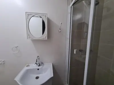 a bathroom with a sink and a shower with a mirror at Zenith House Boston Self Catering Accomodation in Cape Town
