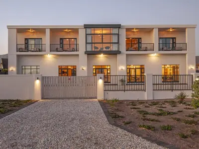 a large white building with windows and a driveway at Glow Boutique Suites & Guesthouse in Hermanus