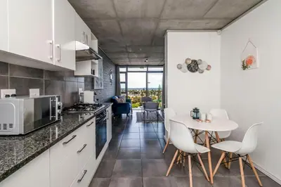 a kitchen with white cabinets and a table and chairs at 2 Bedroom Secure Pool Strong WiFi in Cape Town