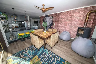 a dining room with a table and a brick wall at The Butterfly Villa in Pringle Bay