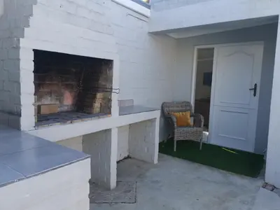 a brick patio with a fireplace and a chair at Gray Cottage in Strand