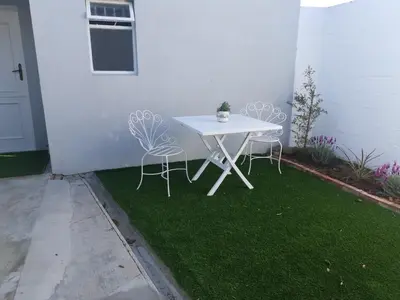 a white table and two chairs on the grass at Gray Cottage in Strand