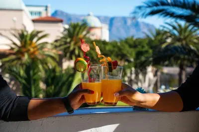 a person holding up a glass of orange juice at Knightsbridge Terrace in Cape Town