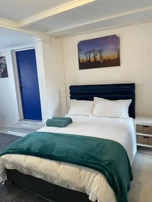 a bedroom with a large bed with a blue headboard at Cub's Home in Cape Town