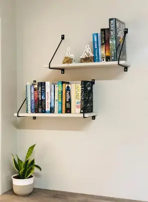 a shelf of books on a wall with a plant at THE CORNER COTTAGE in Somerset West
