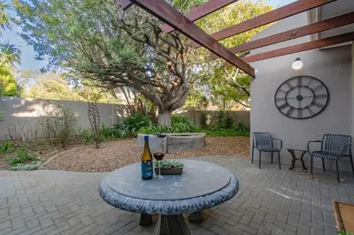 a patio with a table with a bottle of wine at THE CORNER COTTAGE in Somerset West