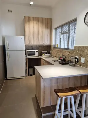 a kitchen with a white refrigerator and wooden cabinets at The Ridge in Cape Town