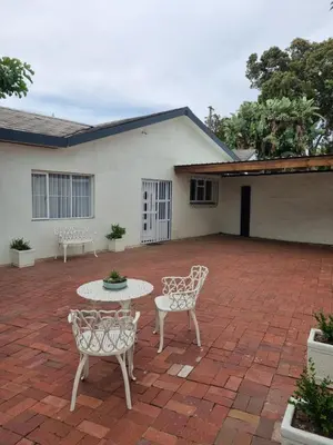 a patio with two chairs and a table in front of a house at The Ridge in Cape Town