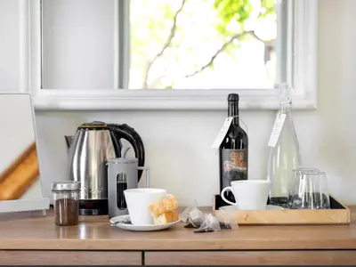 a table with a bottle of wine and two cups at Greyton Lodge in Greyton