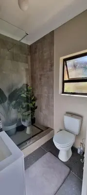 a bathroom with a toilet and a sink and a window at Tranquility Studio in Somerset West