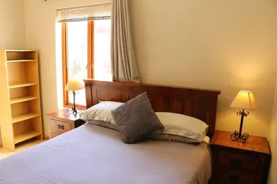 a bedroom with a bed with two lamps and a window at Tranquility Studio in Somerset West