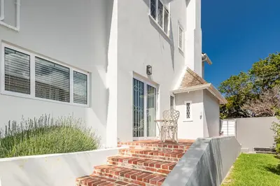 a white house with a brick staircase in front at Spacious Guest Apartment in Rondebosch in Cape Town