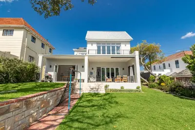 a white house with a fence in the yard at Spacious Guest Apartment in Rondebosch in Cape Town