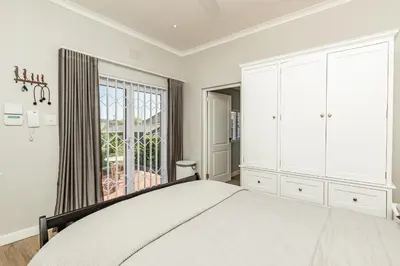 a white bedroom with a bed and a window at Spacious Guest Apartment in Rondebosch in Cape Town