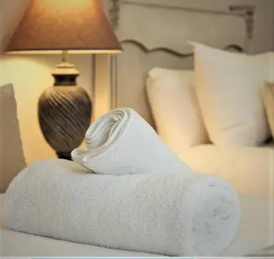 a white towel sitting on a bed next to a lamp at Blouberg,1106 Portico,Cape town in Cape Town