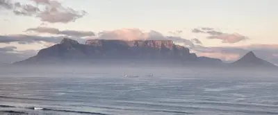 a mountain in the ocean with a boat in the water at Blouberg,1106 Portico,Cape town in Cape Town