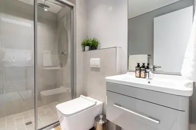 a bathroom with a toilet and a sink and a shower at Burmeister403 - Modern 1 Bedroom Apartment across from Ocean in Cape Town