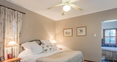 a bedroom with a bed and a ceiling fan at Tuscany Hauss Villa in Somerset West