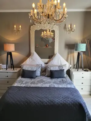 a bedroom with a large bed with a chandelier at Perle Du Cap in Paarl