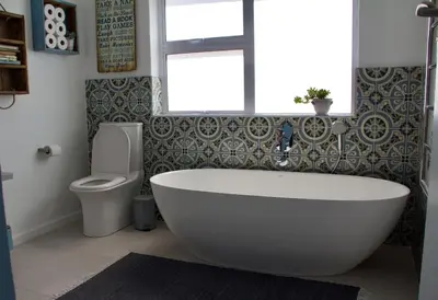 a bathroom with a tub and a toilet and a window at Seafront house with a view in Kleinmond