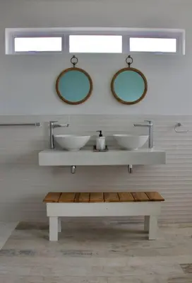 a bathroom with two sinks and two mirrors at Seafront house with a view in Kleinmond