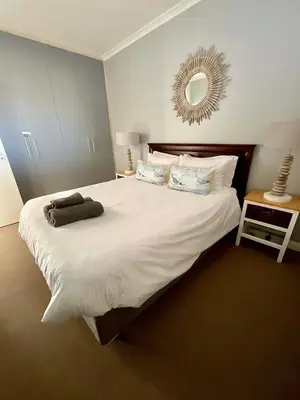 a bedroom with a large white bed with a mirror at 502 Portico in Cape Town