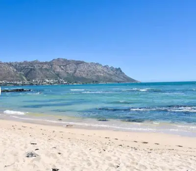 a beach with the ocean and a mountain in the background at 30 Nagua Bay in Cape Town