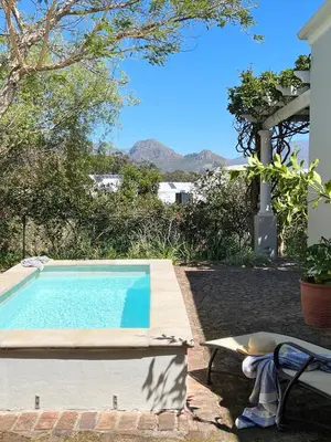a swimming pool with a bench next to a house at La Belle Vie in Franschhoek