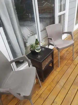 a porch with two chairs and a table with a bottle of wine at Lovely 2 bedroom condo with balcony and a view! in Cape Town