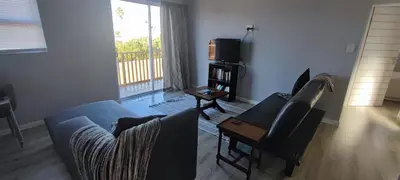 a living room with a couch and a tv at Lovely 2 bedroom condo with balcony and a view! in Cape Town