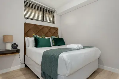 a bedroom with a large white bed with green pillows at Burmeister on Park Apartments in Cape Town