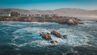 a group of people standing on rocks in the ocean at Oak on Main in Hermanus
