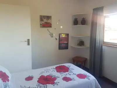 a bedroom with a bed with a white bedspread with red flowers at Relax on Blair in Cape Town