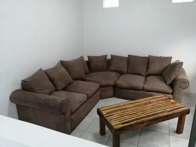a living room with a brown couch and a coffee table at Perfect long stay,near Rondevlei nature reserve,wifi in Cape Town