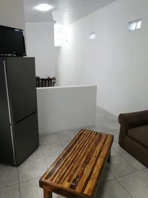 a living room with a table and a refrigerator at Perfect long stay,near Rondevlei nature reserve,wifi in Cape Town