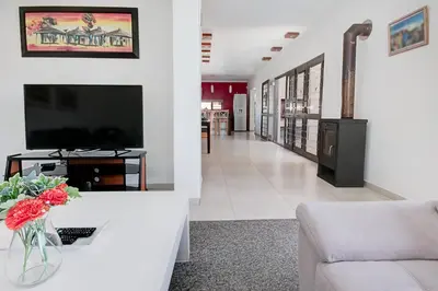 a living room with a television and a living room with a couch at Spacious Shared 3-Bedroom Villa Near Blouberg Beach Pool, Wi-Fi, Braai in Cape Town