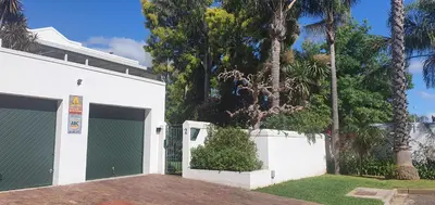 a white building with two garage doors and palm trees at Stellenbosch Paradyskloof Unit in Stellenbosch