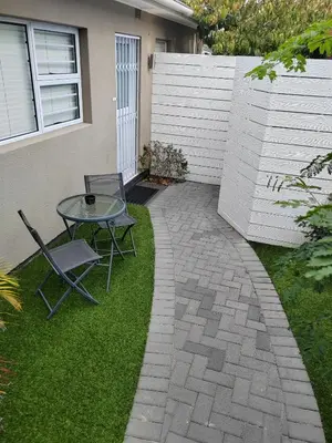 a patio with a table and chairs on the grass at Leafy Retreat Kenridge Trendy in Durbanville