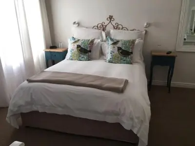 a bedroom with a white bed with two birds on it at Pat's Place in Hermanus