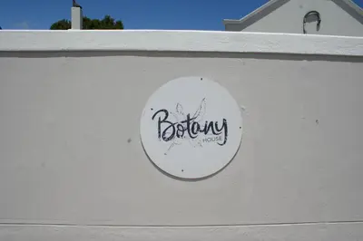 a sign on the side of a white wall at Botany House, in the heart of Hermanus in Hermanus