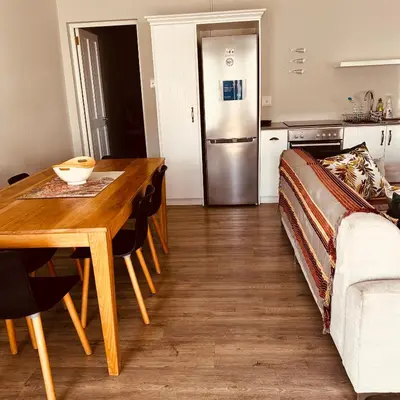a kitchen and dining room with a table and a refrigerator at Botany House, in the heart of Hermanus in Hermanus