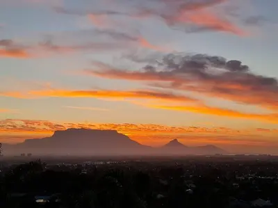 a sunset over a city with a mountain in the background at Palm Zicht MAIN 3 bedroom apartment in Cape Town