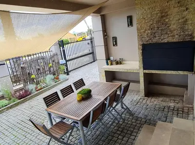 a patio with a wooden table and chairs and a counter at Palm Zicht MAIN 3 bedroom apartment in Cape Town