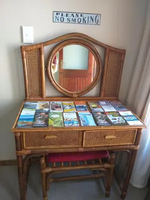 a dresser with a mirror and a table with books at Prince Alfreds in Caledon