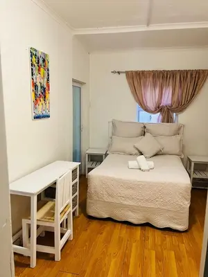 a bedroom with a white bed and a desk at African Haven Guest House in Cape Town