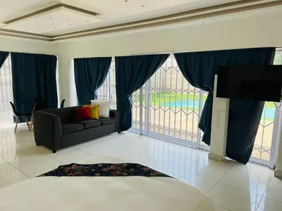 a living room with a bed and a couch and a tv at African Haven Guest House in Cape Town