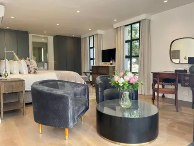 a bedroom with a bed and a table and chairs at Vergenoegd Löw Boutique Hotel & Spa in Somerset West