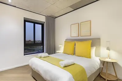 a bedroom with a large bed with yellow pillows at Bridgewater View 502 in Cape Town