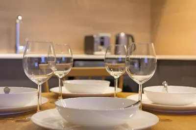 a table with four wine glasses and plates on it at Bridgewater View 502 in Cape Town