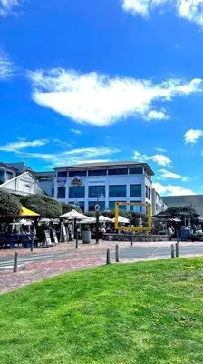a building with tables and umbrellas in front of it at Hermanus Waterfront Apartment No.19 in Hermanus